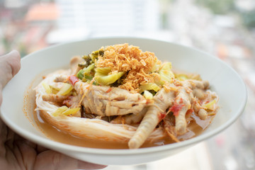 Rice noodles in fish curry sauce with chicken feet.