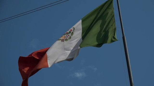 Mexican flag waving in a blue sky.  Shot in high speed photography