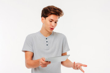 Attractive young man holds tablet in hand on white background