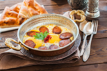 Turkish breakfast  - fried eggs with sausages and spices in a pa