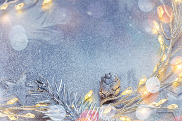 christmas lights and fir tree branch with decorations on silver winter background with copy space