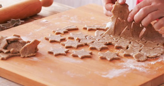 Gingerbread sweets making, extracting star shaped cookies from dough. Close up at hands