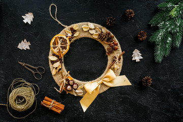 Christmas decoration concept. Creative christmas wreath made of thread near matherials and instruments, sciccors on black background top view