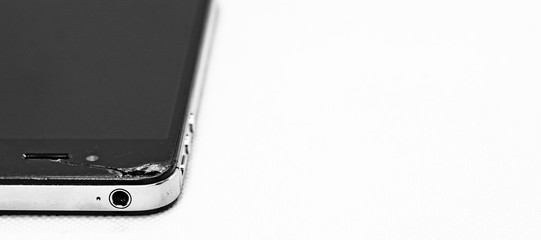 Generic broken black smartphone with a crack, isolated on white background.