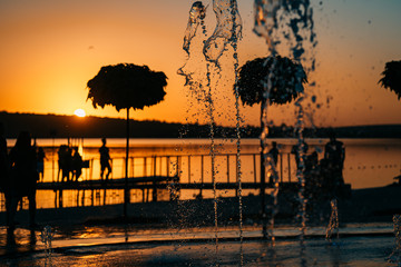 stream of a fountain splashes water, sunset