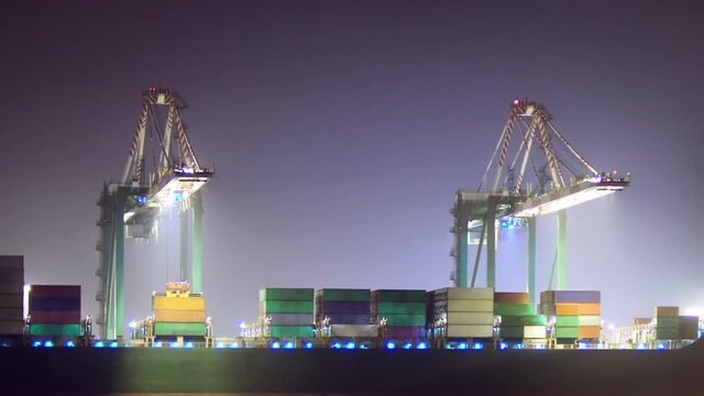 Loading a container ship at night, ZOOM OUT.