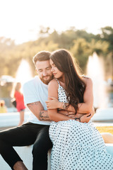 Handsome guy hugs a beautiful girl on a background of a fountain