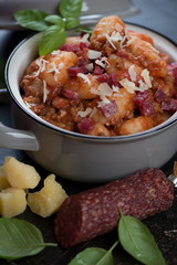 Potato gnocchi served with ground meat, salami and grated parmesan in a pan, selective focus, studio shot