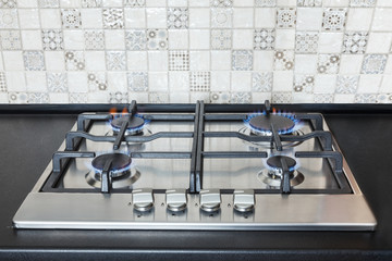 Stainless steel kitchen surface with cast-iron grill. Burning gas burners