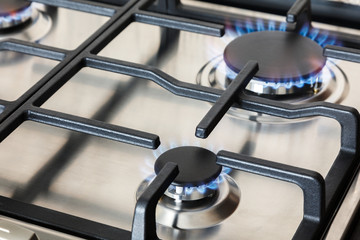 Stainless steel kitchen surface with cast-iron grill. Burning gas burners