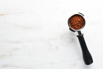 Holder from a coffee machine with coffee. On a white wooden background. Top view. Free copy space.