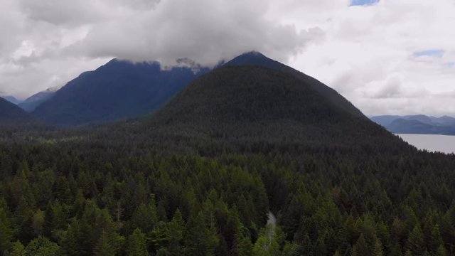 Aerial, rising pan, drone shot, of mountains, green forest and a lake, on a cloudy day, in Golden ears provencial park, in British Columbia, Canada