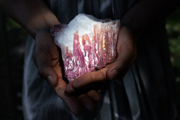 Woman holding pink tourmaline in quartz crystal in powerful healing concept