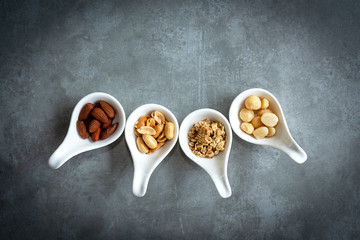 Healthy Foods. Mixed nuts in white bowls with nuts for diet on a concrete table. Different kinds of tasty and healthy nuts. Top view and copy space.  Healthy Concept.
