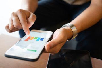 Asian woman looking at some charts on her mobile phone while sitting at coffee shop
