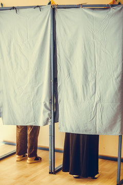 Persons voting in booths at a polling station