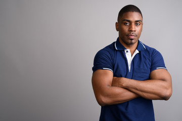 Young handsome African man wearing blue polo shirt against gray  - Powered by Adobe