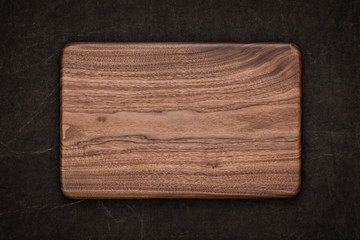 Handmade black walnut rectangular chopping board on handmade smeared burlap, walnut texture background