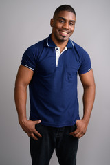 Young handsome African man wearing blue polo shirt against gray 