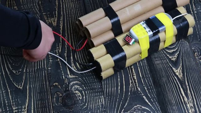 the process of neutralization of an explosive device, a snack on the red wire on a dark wooden background.