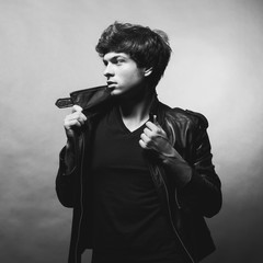 Portrait of Handsome Young Man. A Men in a Leather Jacket posing on a Gray Background. Black And White Photo