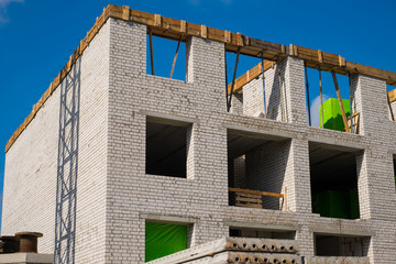 Fototapeta na wymiar Construction of a brick multi-storey building against the blue sky.