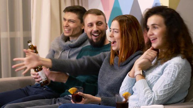 Group of people enjoy carefree time. Sit on sofa and watch smart TV. Celebration concept