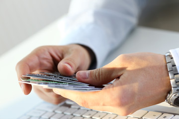 Male arms hold and count bunch of credit cards