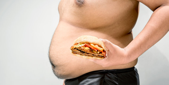 Man with overweight belly holding hamburger on his hand