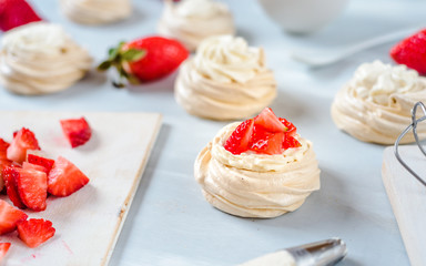 Strawberry pavlova cake nests, meringue decoration on a culinary table