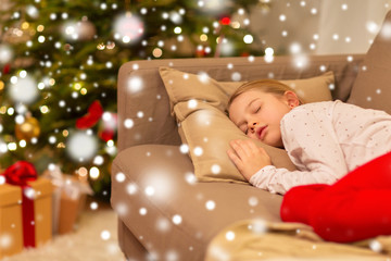 christmas, holidays and childhood concept - girl sleeping on sofa at home