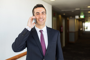 business trip, people and communication concept - happy smiling businessman calling on smartphone...