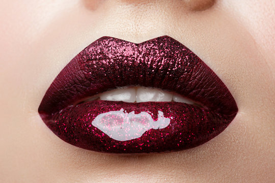 Close up view of beautiful woman lips with dark red lipstick. Fashion make up. Cosmetology, drugstore or fashion makeup concept. Studio shot