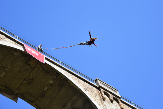 Beautiful Young Girl With Long Ponytail Performing Bungee Jump From Railway Bridge