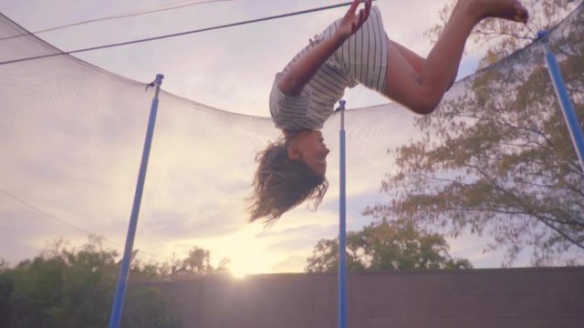 Girl jumping on trampoline outdoors. Slow motion.