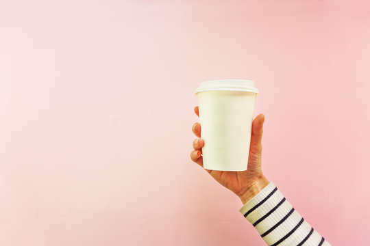 Creative mock up image of woman hand holding craft paper coffee cup with copy space isolated on white background in minimalism style. Template for feminine blog, social media