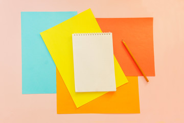 Top view flat lay picture with blank notepad page and different accessories on colored surface