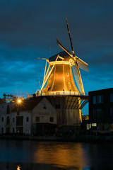 Fototapeta na wymiar A typical dutch windmill is illuminated by lights during blue hour