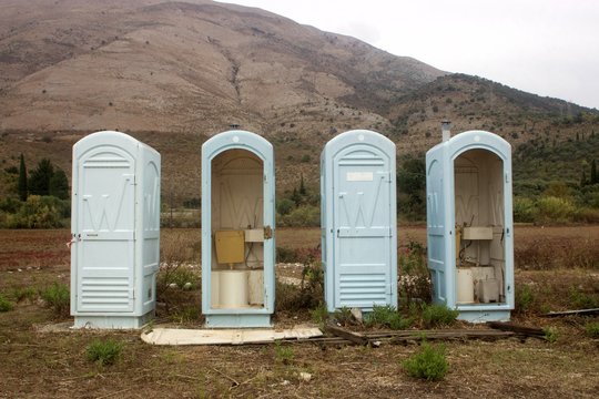Group of abandoned dirty camping cabin plastic toilets in a campsite by the beach