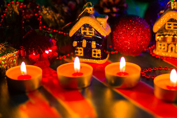 Merry Cristmas. Toy houses and candlelight. Christmas decorations on blurred background. Festive evening. Spruce branches and Christmas toys with bokeh. Copy space