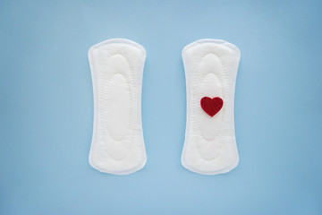 Menstrual pads with red heart on color background
