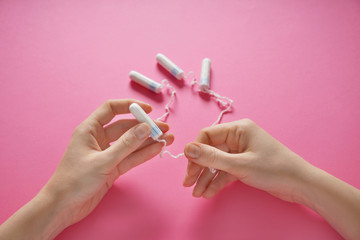 Woman holding tampons on color background