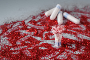 Tampon with red glitters on grey background