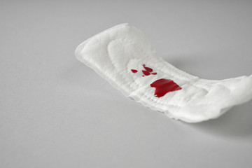 Menstrual pad with red stain on grey background