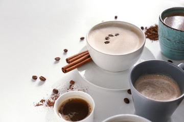 Many cups with tasty aromatic coffee on white background