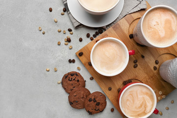 Many cups with tasty aromatic coffee and cookies on grey table