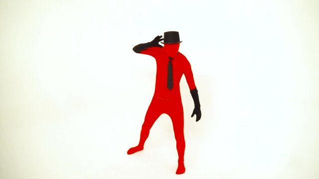 A weird man in a red suite, long black gloves, tie and a top hat dancing in a white studio