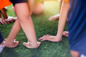 Children's hands on green artificial turf.