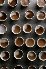 Many plastic cups with tasty aromatic coffee on dark background, flat lay