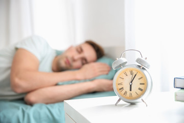Alarm clock on table in bedroom of young man